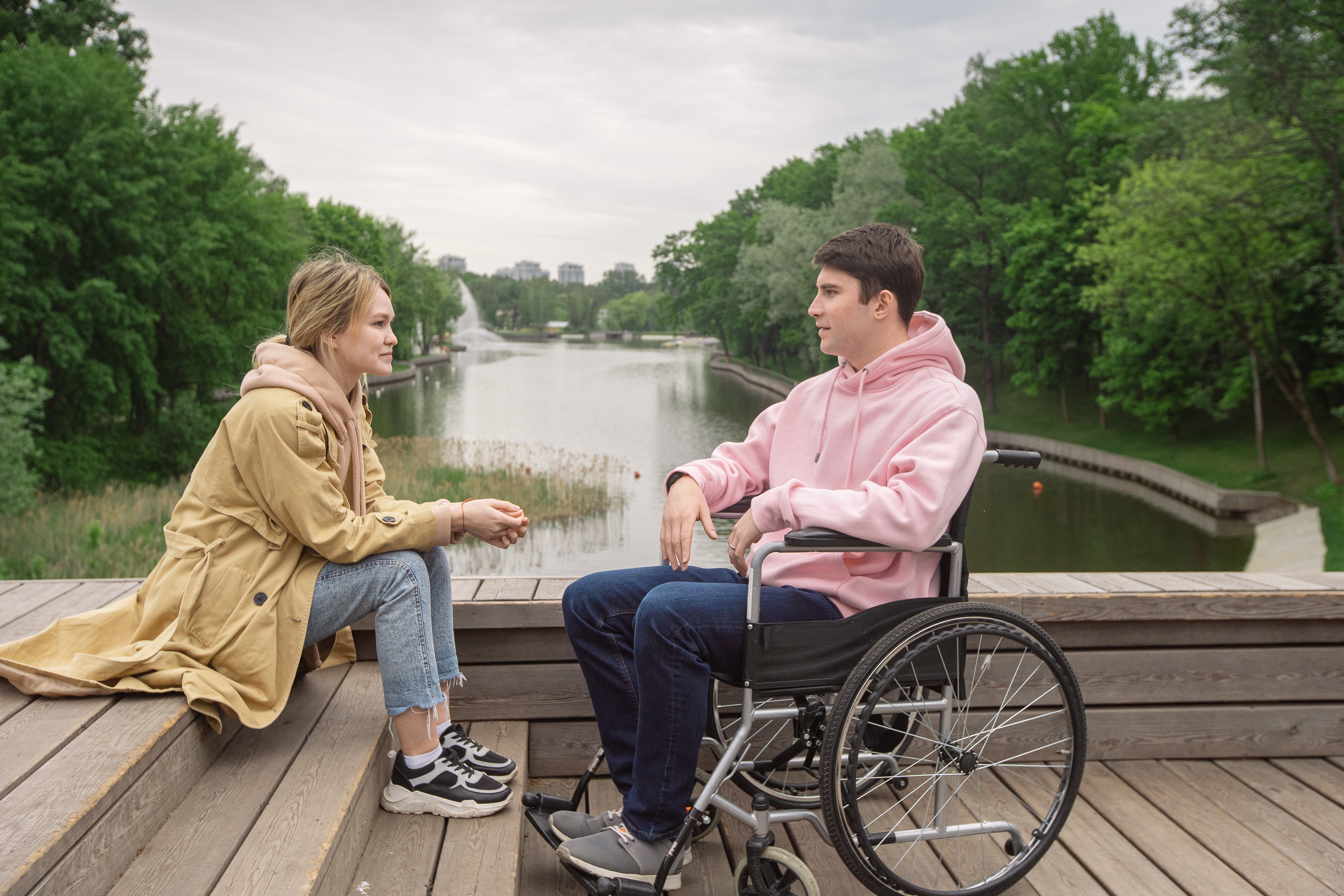 Woman and man in wheelchair talking by river